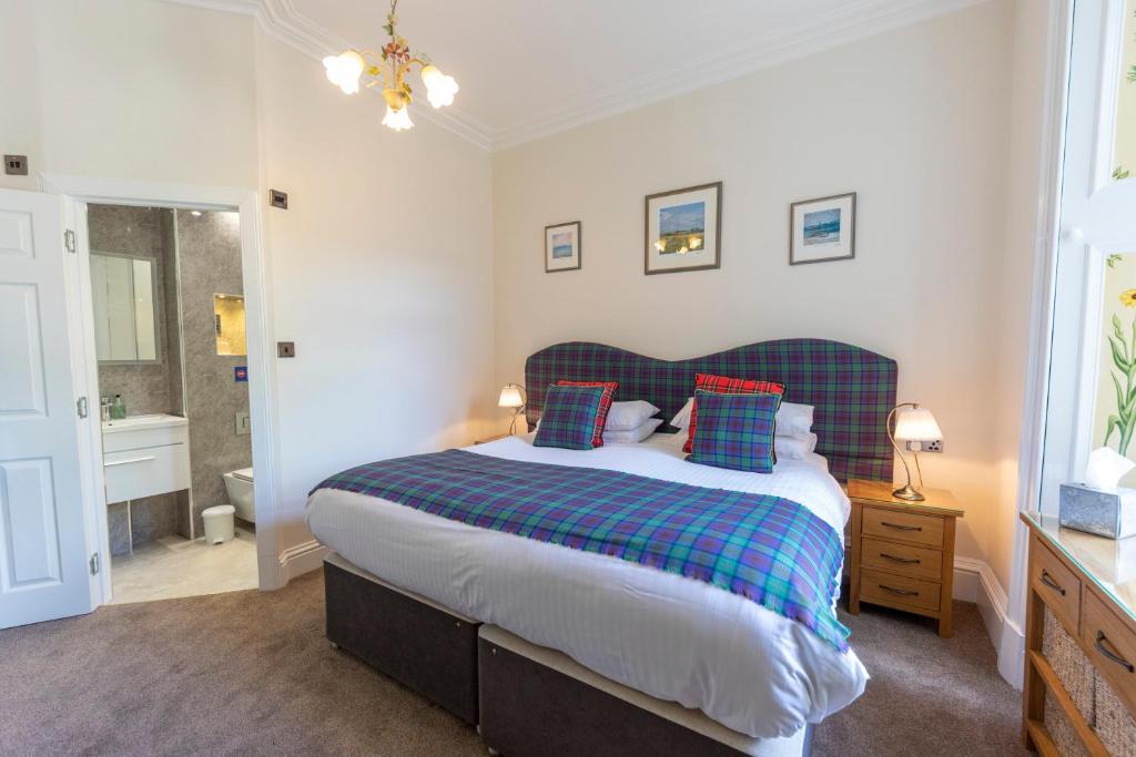 um quarto com uma cama grande com almofadas azuis e vermelhas em Montague Guest House em St. Andrews