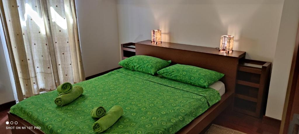 a bedroom with a bed with green sheets and pillows at Apartment Višnja in Vodice