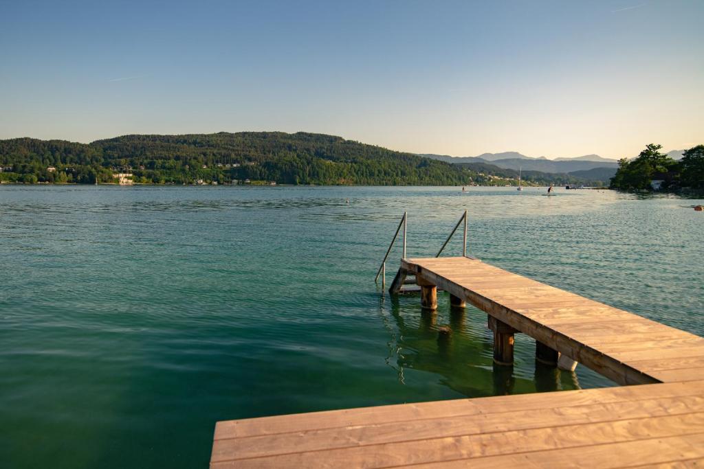 ein Holzsteg auf einem See mit Bergen im Hintergrund in der Unterkunft Seeappartements Christiane Haus 95 in Leinsdorf