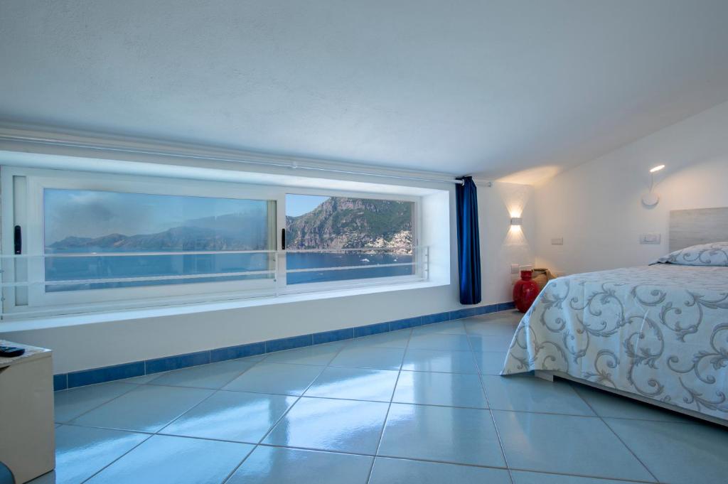 een slaapkamer met een bed en een groot raam bij La Mansarda in Praiano