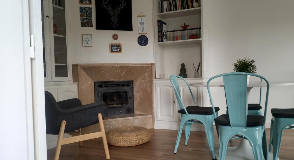 ein Wohnzimmer mit einem Tisch, Stühlen und einem Kamin in der Unterkunft Amália Rodrigues -apartamento com 3 quartos em pleno coração de Ílhavo in Ílhavo