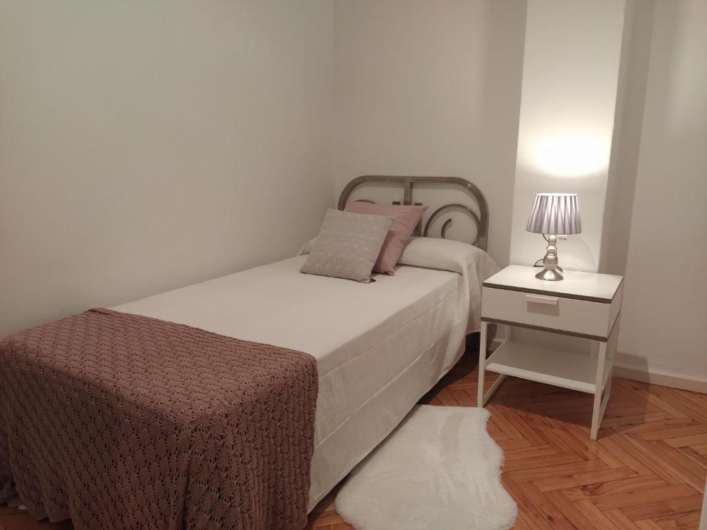 1 dormitorio con 1 cama y 1 mesa con lámpara en Bonito piso en el centro de Ourense, en Ourense