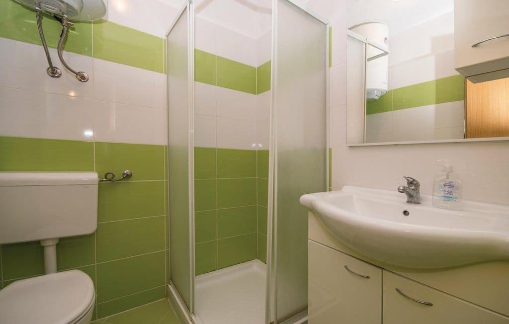 a green and white bathroom with a sink and a shower at Apartmani Andrija in Pakoštane