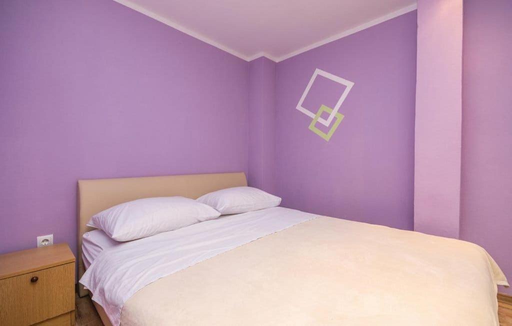 a bedroom with purple walls and a white bed at Apartmani Andrija in Pakoštane