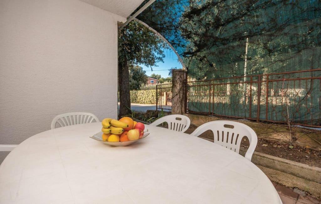 a bowl of fruit on a white table with chairs at Apartmani Andrija in Pakoštane