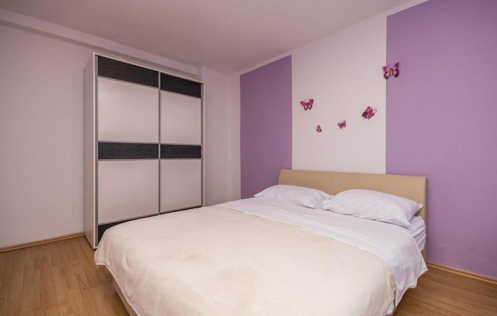 a bedroom with a white bed and purple walls at Apartmani Andrija in Pakoštane