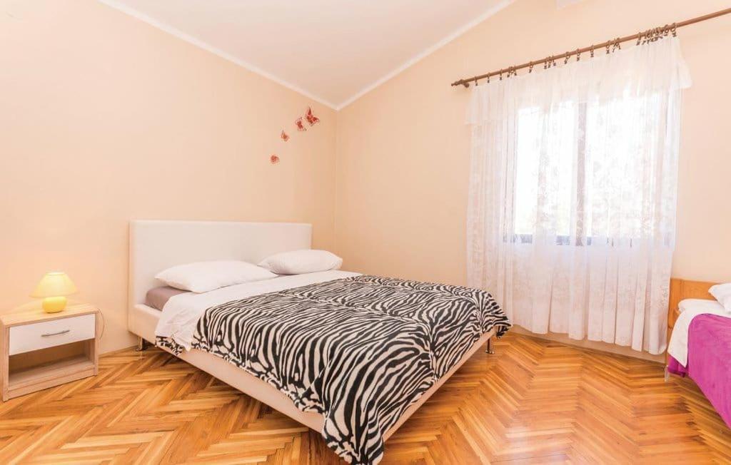 a bedroom with a zebra print bed and a window at Apartmani Andrija in Pakoštane