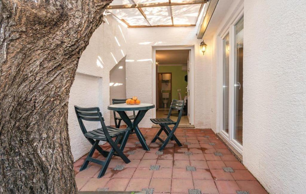 a patio with two chairs and a table with oranges on it at Apartmani Andrija in Pakoštane