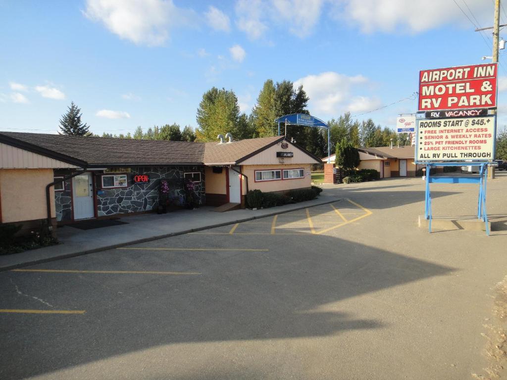 a parking lot with a sign in front of a building at Airport Inn Motel in Quesnel