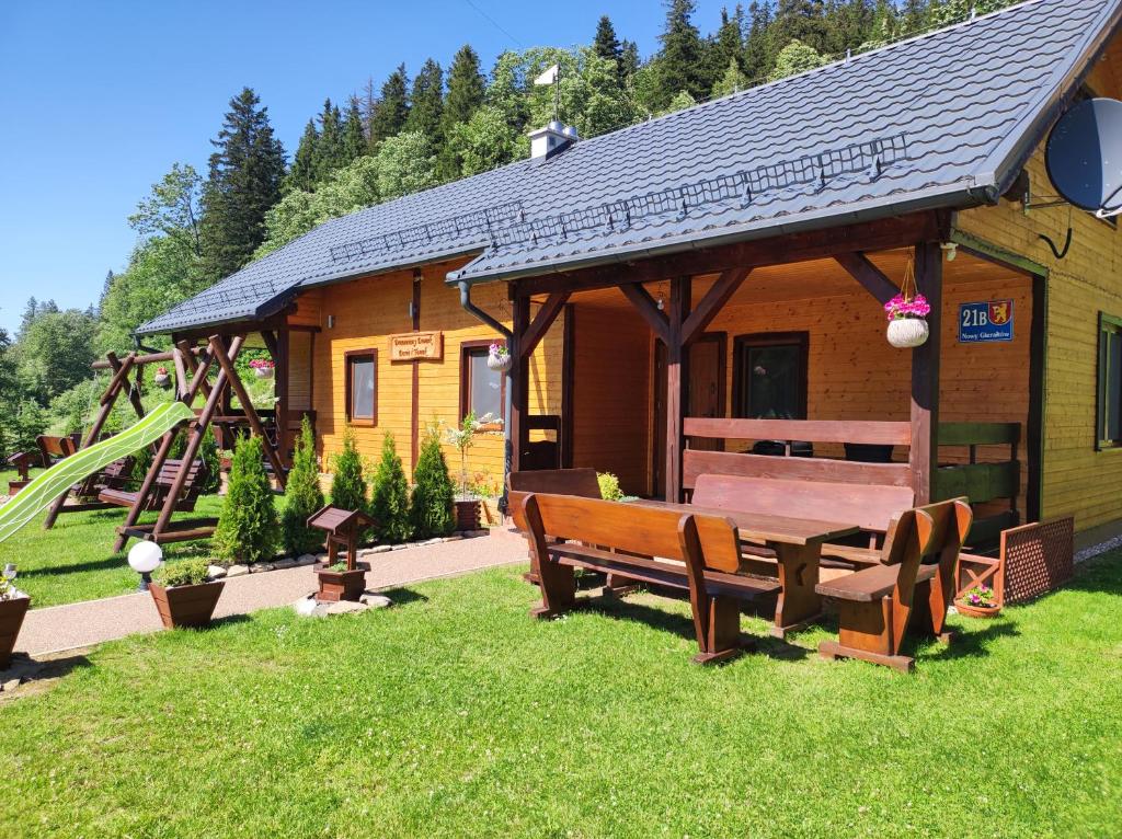 a wooden cabin with a bench and a playground at Drewniany Domek Daria i Tomek 2 domki na 8 osób in Stronie Śląskie