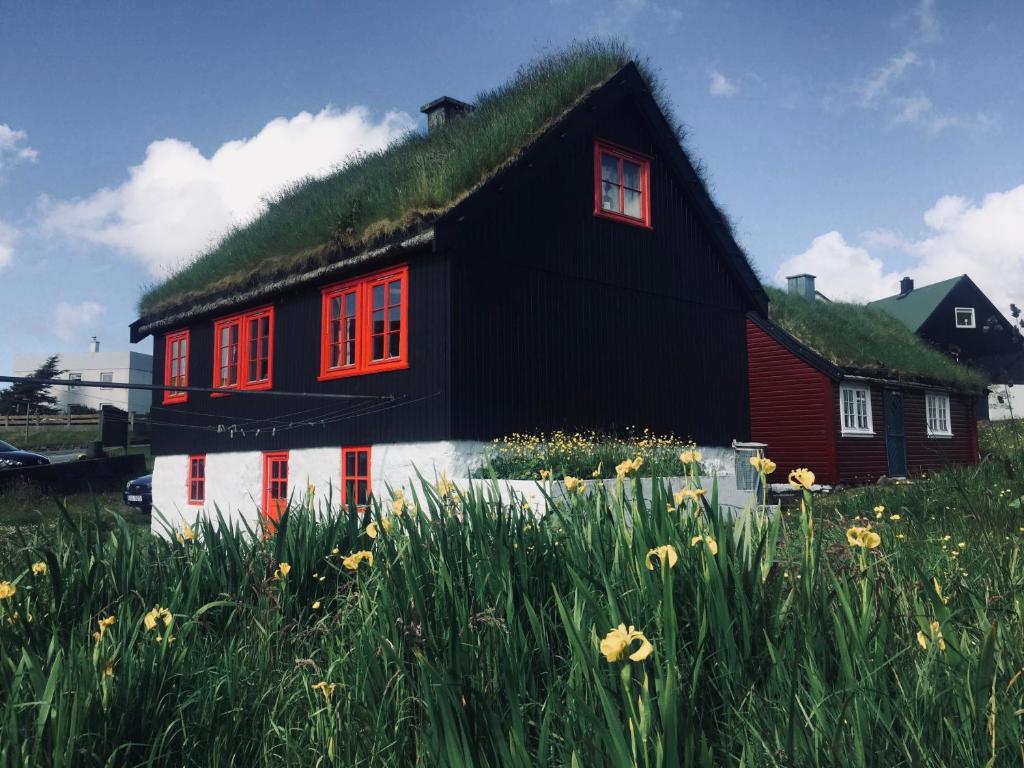 a black and white house with a grass roof at Turf House Cottage - Near Airport in Miðvágur