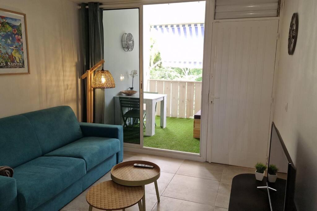 uma sala de estar com um sofá azul e uma mesa em Appartement 500 mètres de la plage à GOSIER em Le Gosier