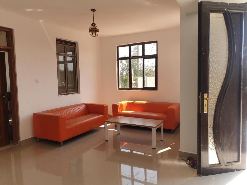 a living room with an orange couch and a table at 401 Restaurant & Accommodation in Naivasha
