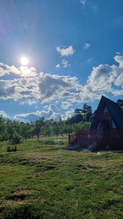 a barn in a field with the sun in the sky at A Pine vikendica u srcu Zapadne Srbije in Nova Varoš