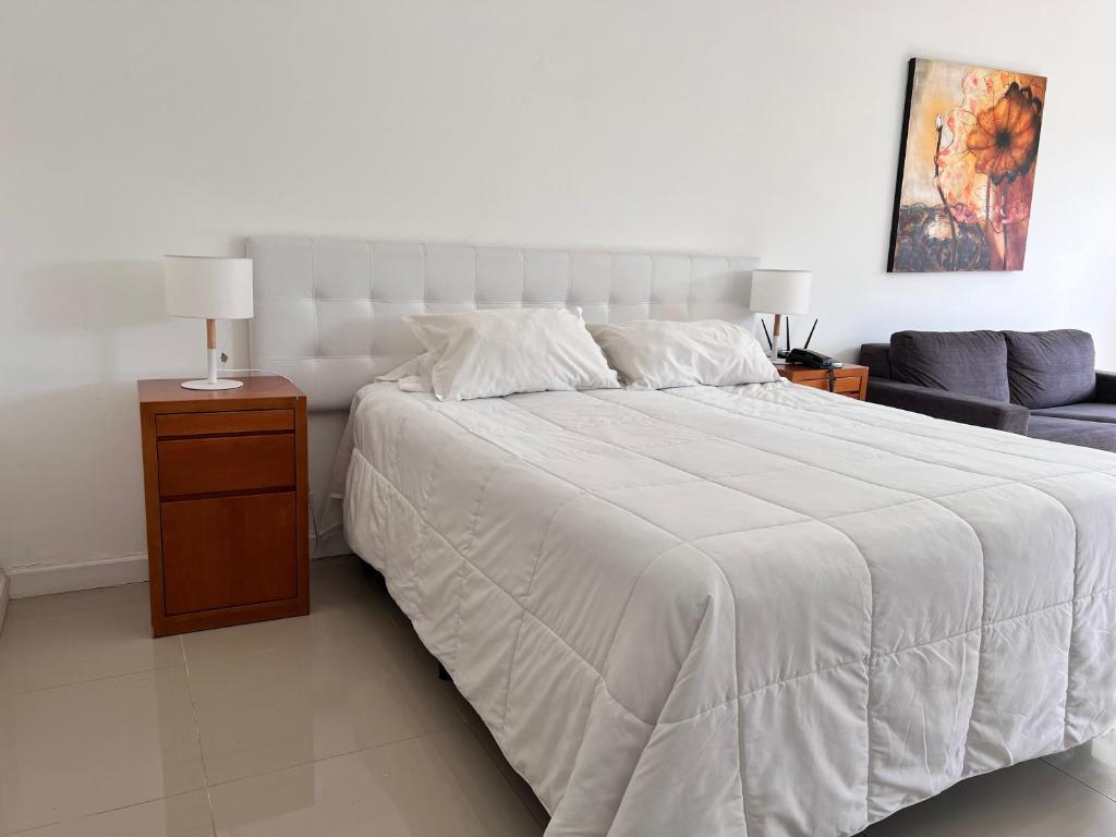 1 dormitorio con 1 cama blanca grande y 1 sofá en Monoambiente Green Park, en Punta del Este