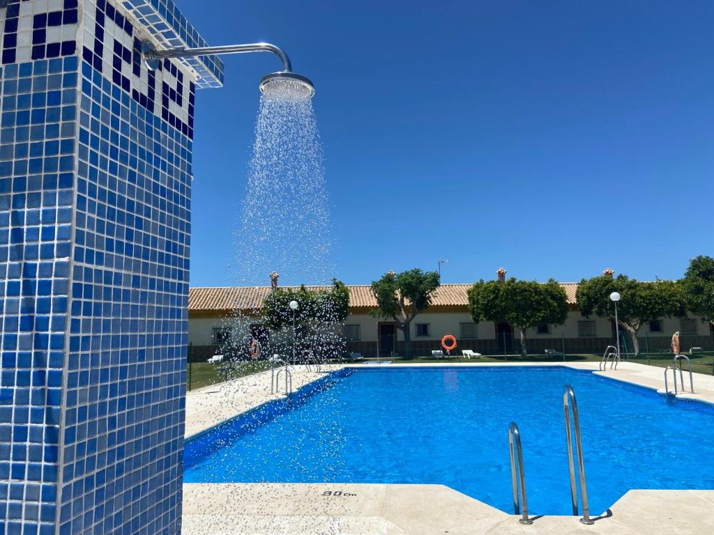 a swimming pool with a fountain next to a building at Hostal Los Mellizos in Conil de la Frontera