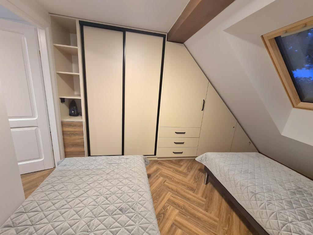 sypialnia na poddaszu z białymi szafkami i łóżkiem w obiekcie Apartament nad BRDĄ , agroturystyka. w mieście Raciąż