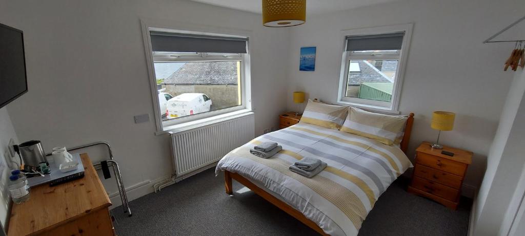 a bedroom with a bed and two windows at Cala Sith Guesthouse in Port Ellen