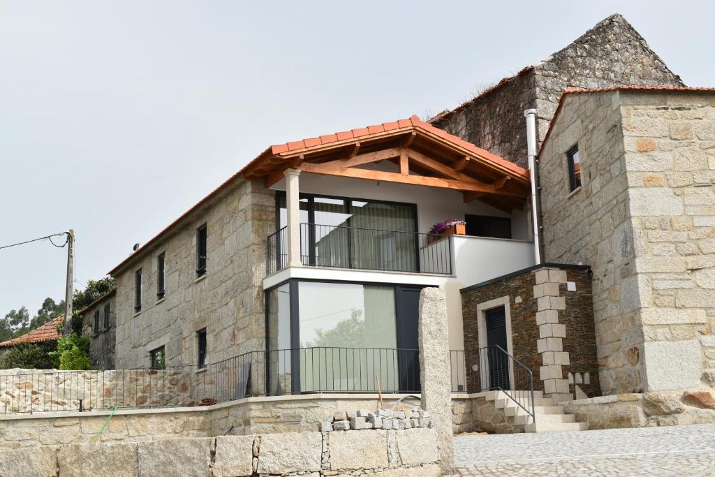 a brick house with a balcony on top of it at Casinhas da eira caramulo turismo rural in Arca