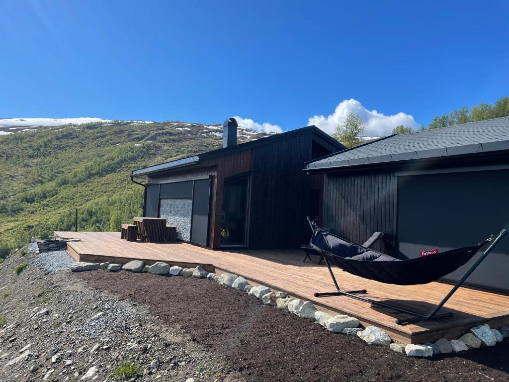 a hammock on a deck next to a cabin at Cabin at the top of Hodlekve. Ski in/ski out. in Sogndal