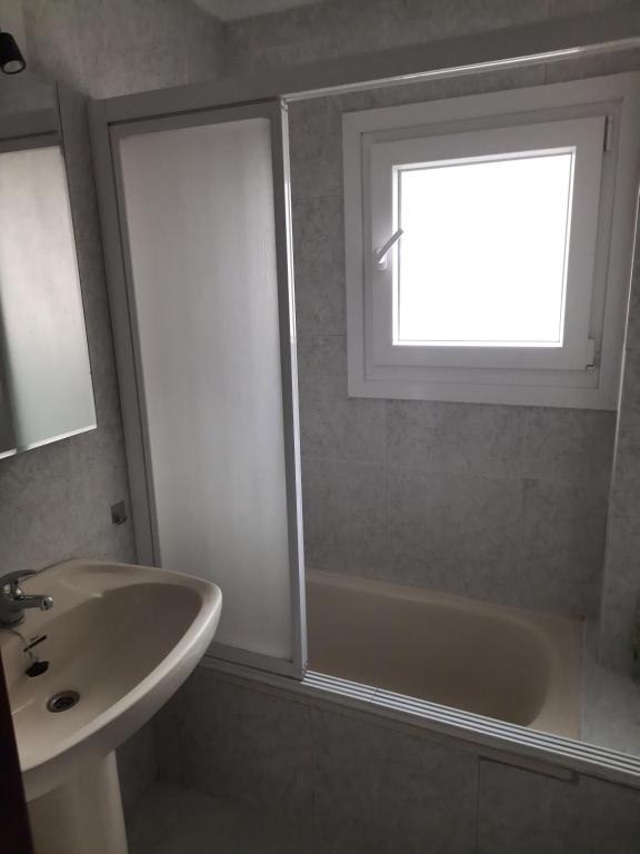 ein Badezimmer mit einem Fenster, einer Badewanne und einem Waschbecken in der Unterkunft Tranquilo piso en Cimadevilla in Gijón