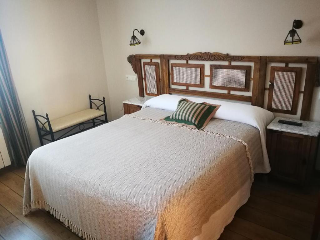 a bedroom with a large white bed and a chair at Hotel rural La Campanona in Villager de Laciana