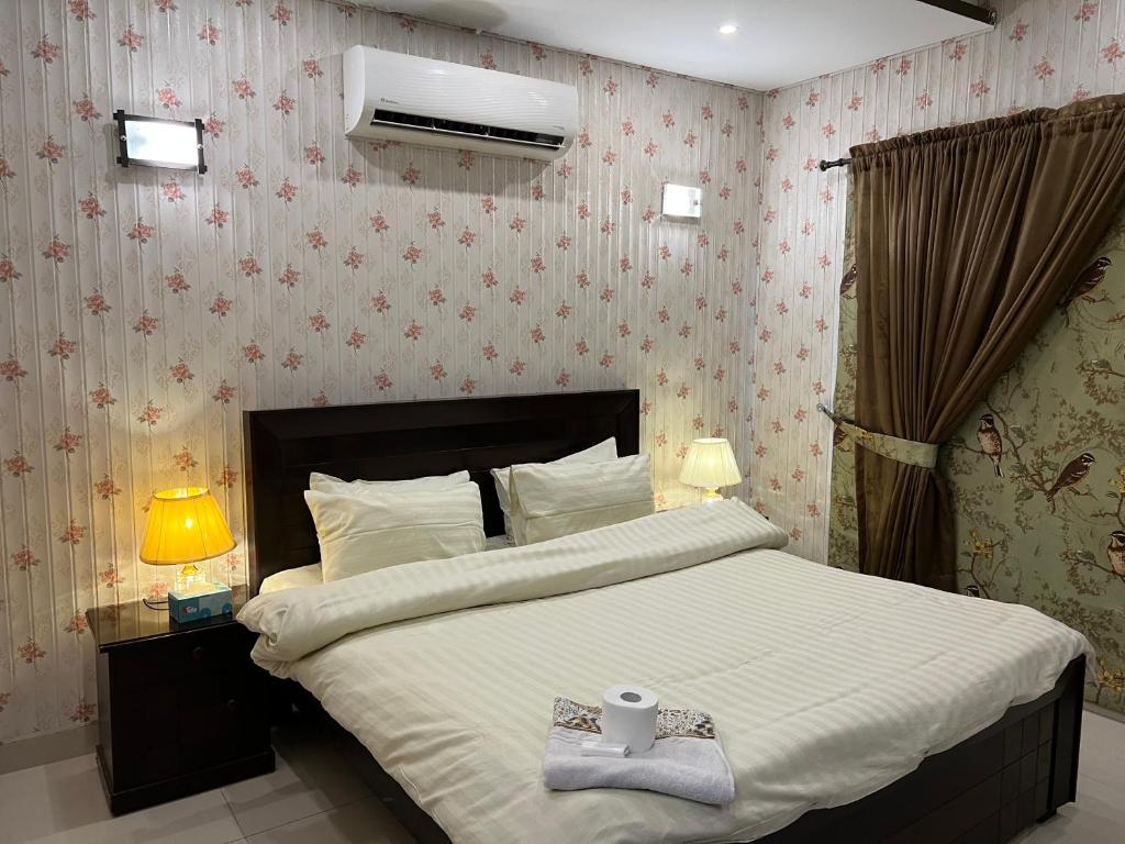 - une chambre avec un grand lit et une serviette dans l'établissement Royal Three Bed Room Full House Dha Phase 6 Lahore, à Lahore