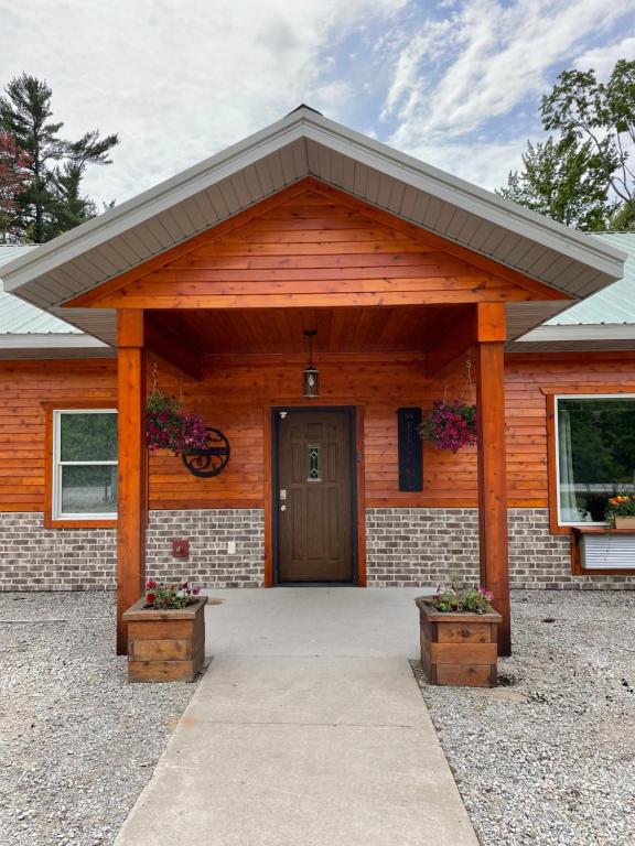 uma casa com uma porta de madeira e dois vasos de flores em Timberwolf Lodge em Manistique