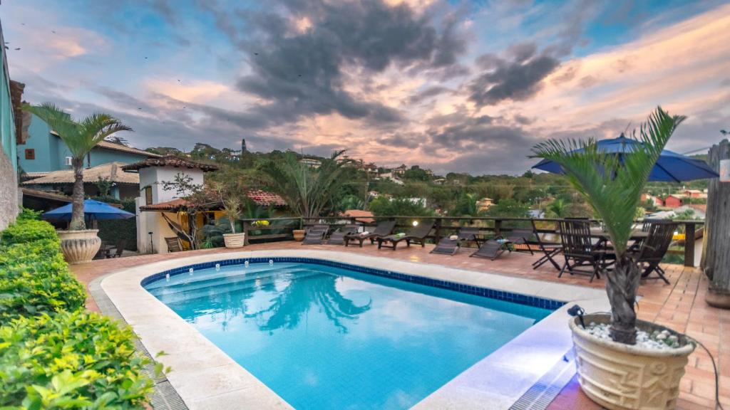 a swimming pool in a yard with chairs and tables at Villa Geriba in Búzios