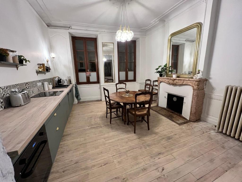 uma cozinha e sala de jantar com uma mesa e uma lareira em Maison dans quartier historique : La Grenouille em Avallon