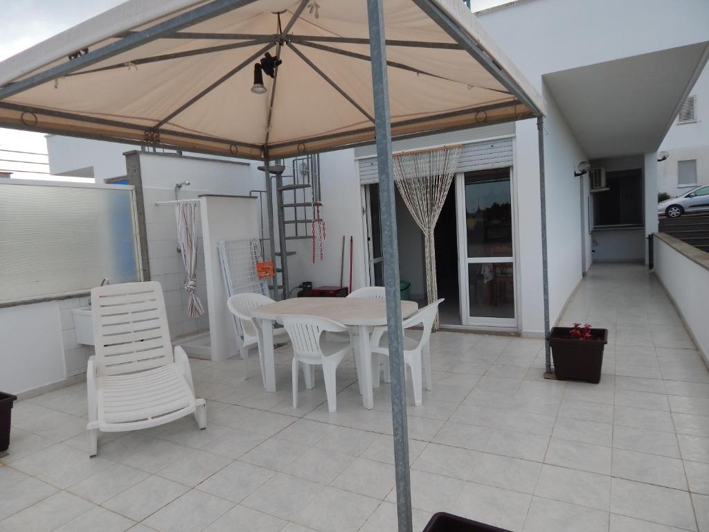 un patio con tavolo e sedie bianchi e ombrellone di Otranto Green House a Otranto