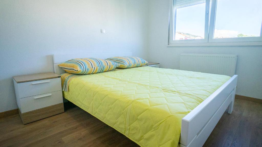 a bedroom with a bed with yellow sheets and a window at Casa llena in Seget Vranjica