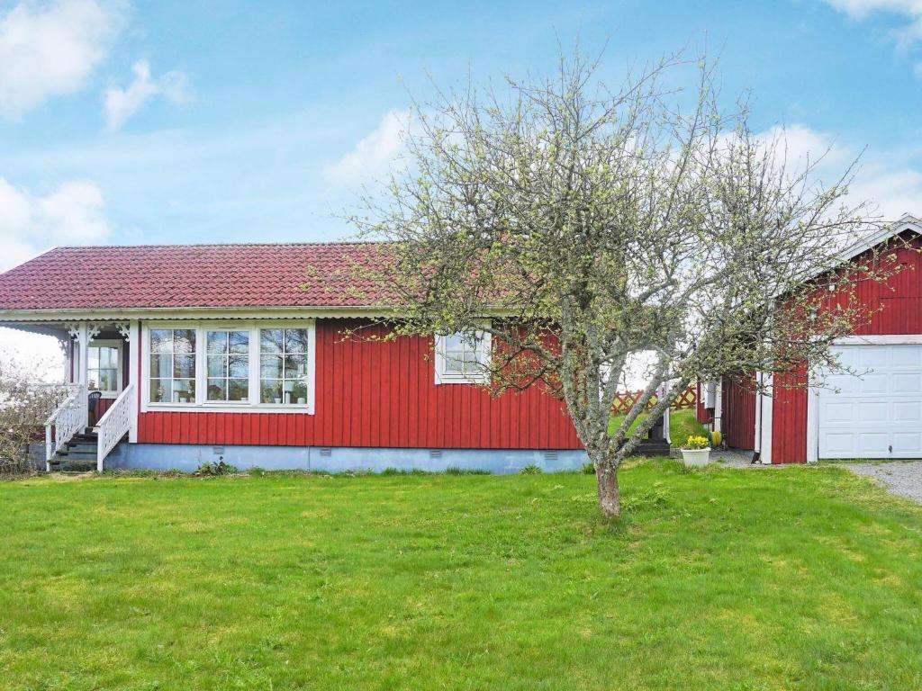 a red house with a tree in front of it at Holiday home LÅNGASJÖ in Långasjö