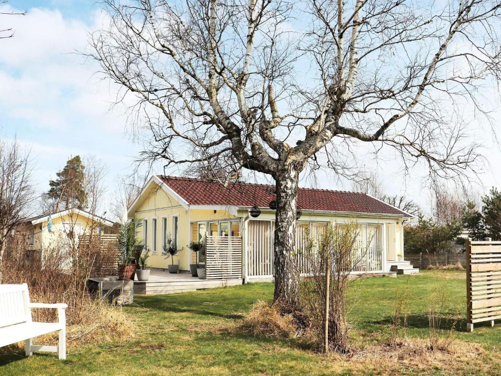 une maison jaune avec un arbre dans la cour dans l'établissement Holiday home MELLBYSTRAND X, à Mellbystrand