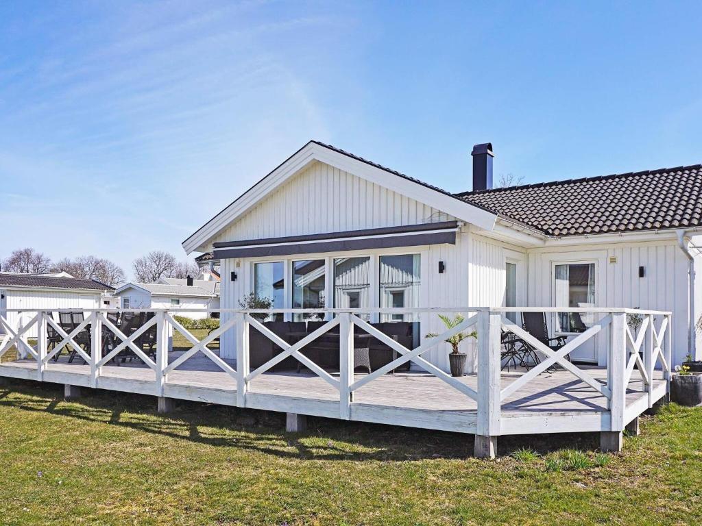 ein weißes Haus mit einer großen Holzterrasse in der Unterkunft Holiday home KÖPINGSVIK VI in Köpingsvik
