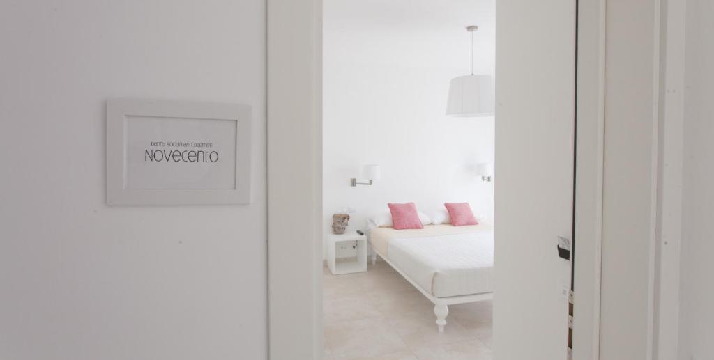 a white bedroom with a bed with pink pillows at Camere Maré in Sirolo