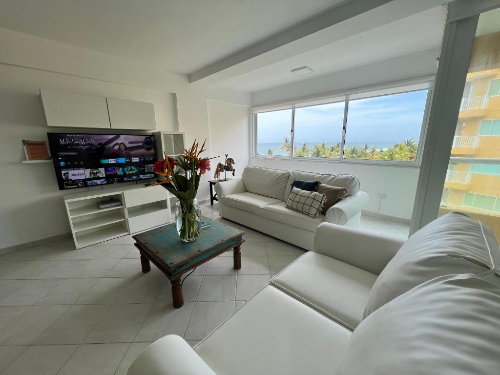 sala de estar con muebles blancos y TV en Cimarron Suites Playa Parguito, en Aricagua