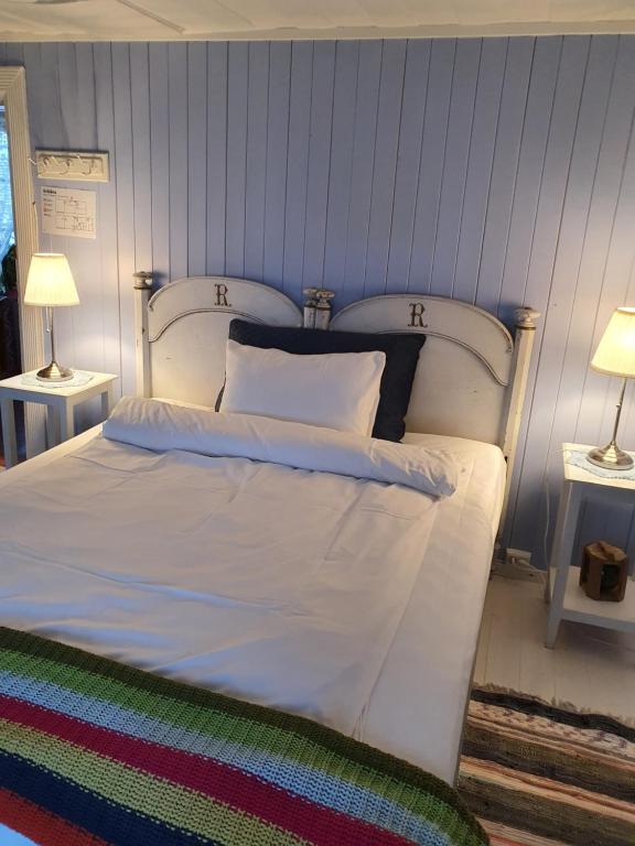 a bedroom with a white bed with two lamps at Handelsstedet Forvik in Vevelstad