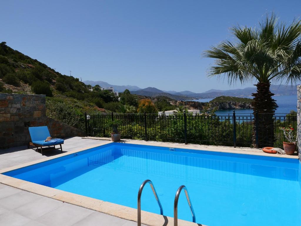 una piscina con palmeras y montañas de fondo en Istron Collection Villas, Villa Selini, en Istron