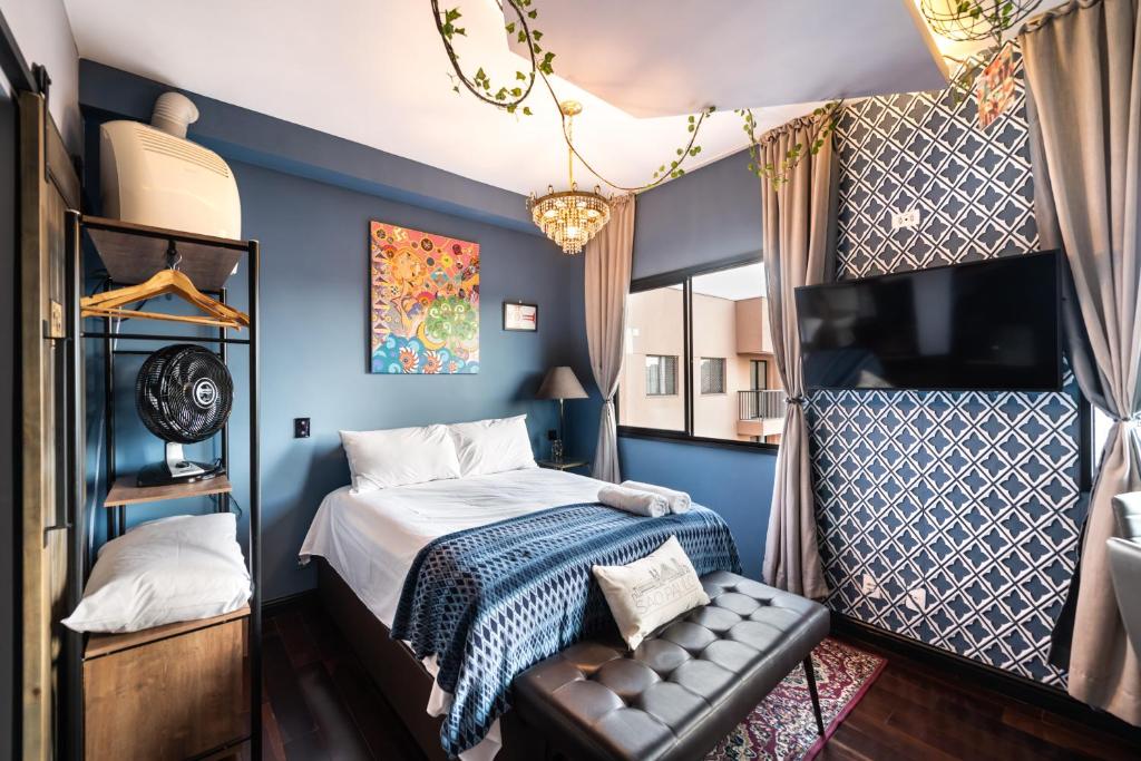 Schlafzimmer mit blauen Wänden und einem Bett mit einer Bank in der Unterkunft SAMPA apartamento inteiro, Completo e Confortável in São Paulo
