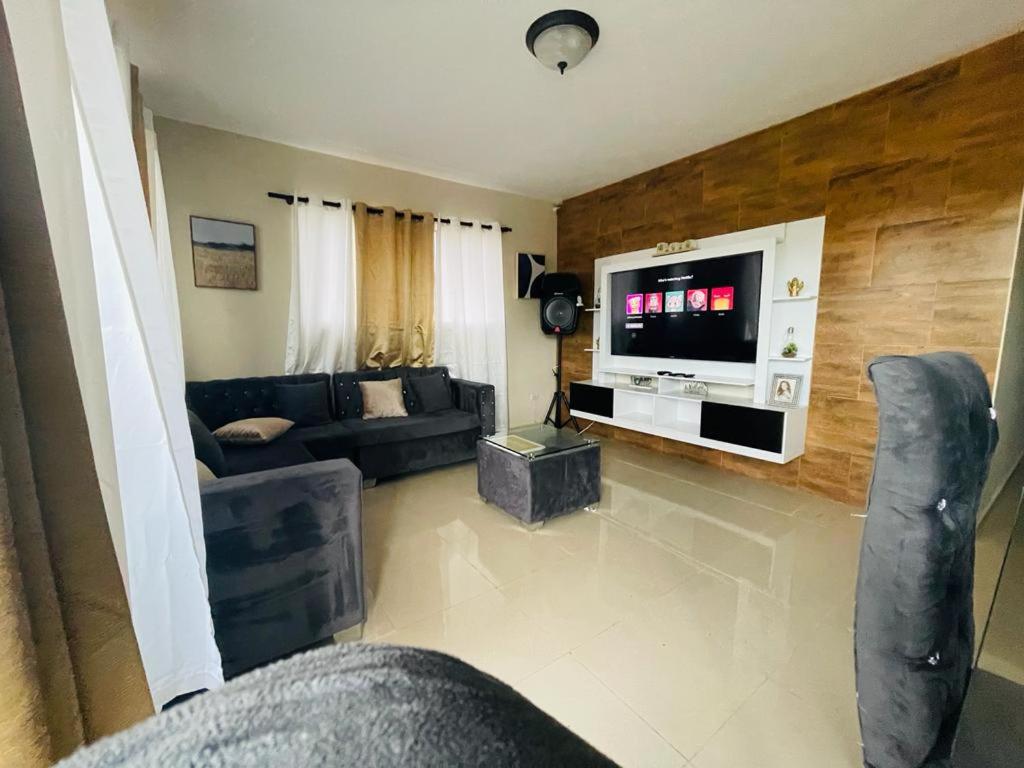 a living room with a couch and a tv at Condo 3 Bd Apt Internet,2 Parqueo,lavadora,ac in San Francisco de Macorís