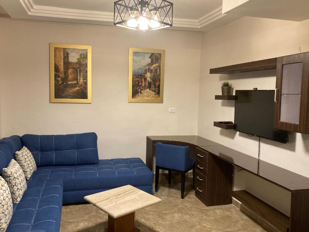 a living room with a blue couch and a tv at The Royal Luxury Superior Queencot in Amman