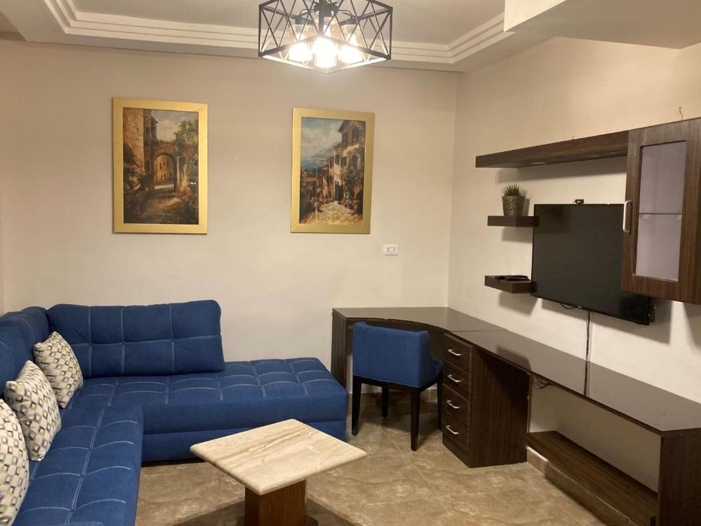 a living room with a blue couch and a tv at The Royal Luxury Superior Queen cot in Amman