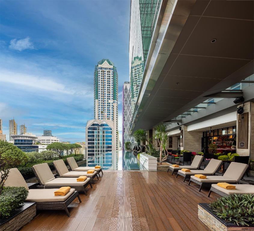 a balcony with lounge chairs and a view of a city at Eastin Grand Hotel Sathorn in Bangkok