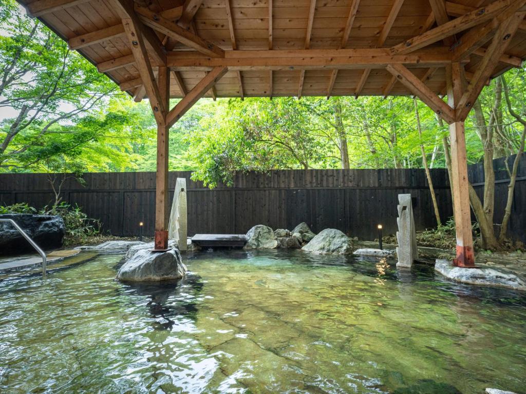 a pool of water with a wooden pergola at KAMENOI HOTEL Nikko Yunishigawa in Nikko