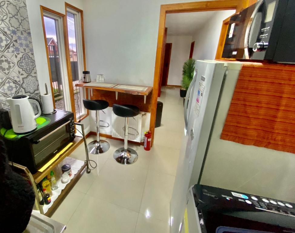 a kitchen with a refrigerator and a table with stools at Hostal Ejecutivo in Victoria