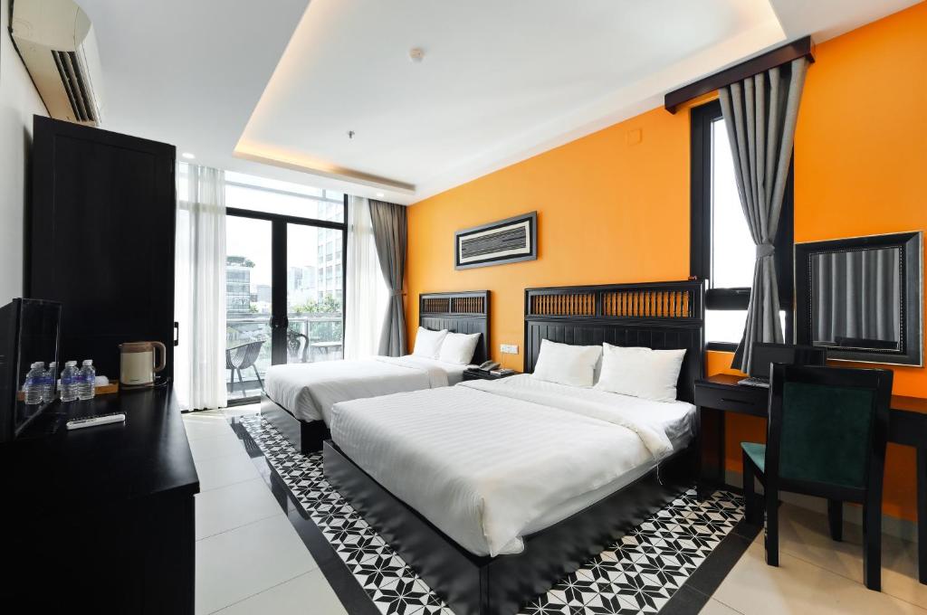 two beds in a room with orange walls at Ohana Hotel - Near Bitexco in Ho Chi Minh City