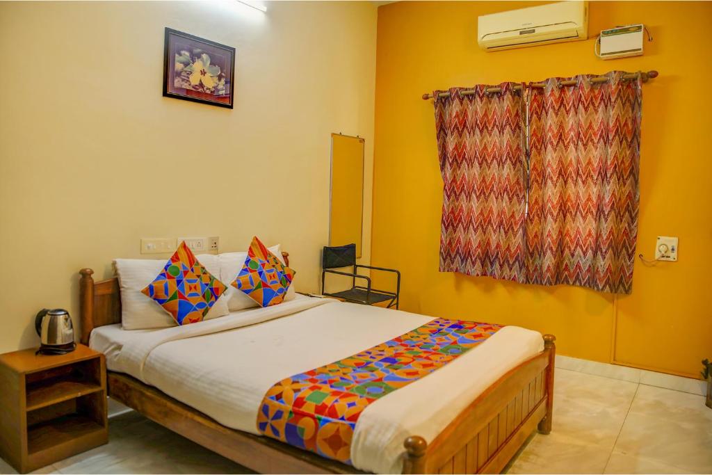 a bedroom with a large bed with colorful pillows at FabHotel Hibiscus Stays in Chennai