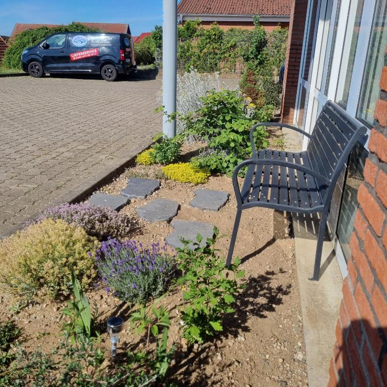 a black bench sitting outside of a house with flowers at Müritz-Pension Waren in Waren