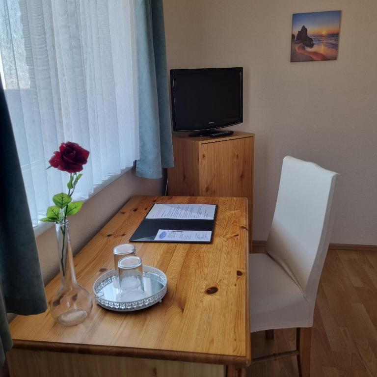 a wooden table with a vase with a flower on it at Müritz-Pension Waren in Waren